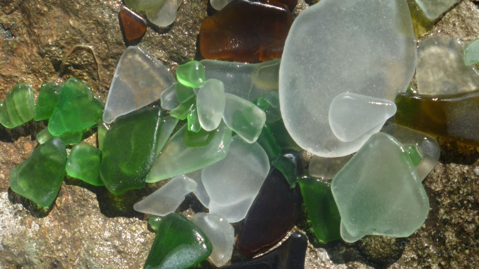 Green, white and brown beach glass on the shores